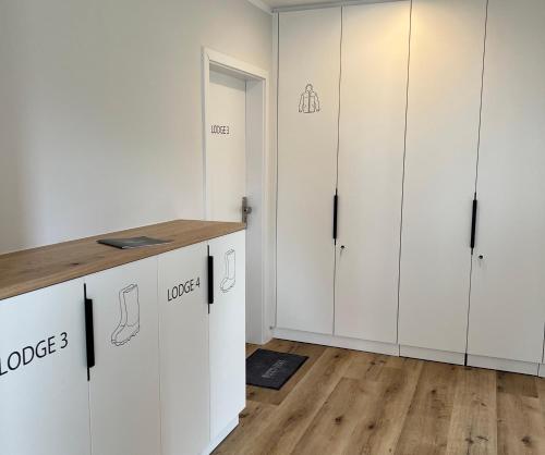 a kitchen with white cabinets and a wooden floor at Dünen Lodge 3 in Juist