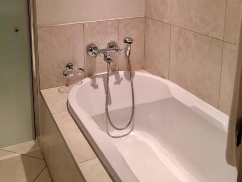 a bath tub with a shower in a bathroom at Apartment in Sandton in Johannesburg