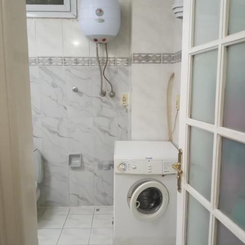 a white bathroom with a washing machine in it at Mall view in Alexandria