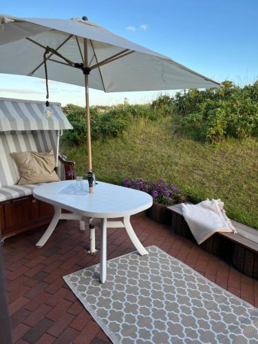 una mesa blanca con sombrilla en el patio en Hus an de Waterkant, en Juist