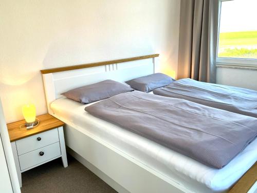 1 dormitorio con 1 cama blanca y ventana en Hus an de Waterkant, en Juist