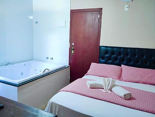 a bedroom with a bed and a bath tub at Pousada Recanto do Chalé Ltda in Macacos