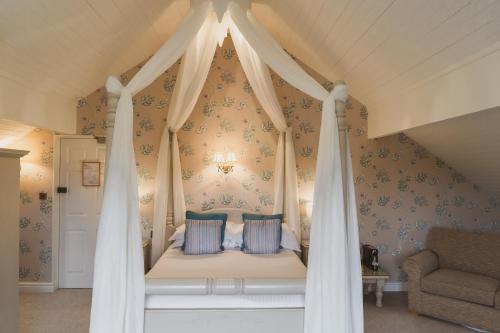 a bedroom with a canopy bed with blue wallpaper at Cragwood Country House Hotel in Windermere