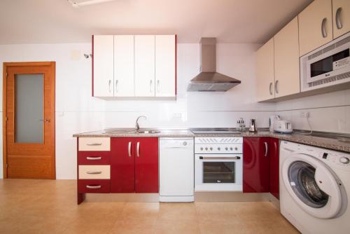 a kitchen with red cabinets and a washing machine at Apartamentos Moon Dreams Puerto in El Puerto de Santa María