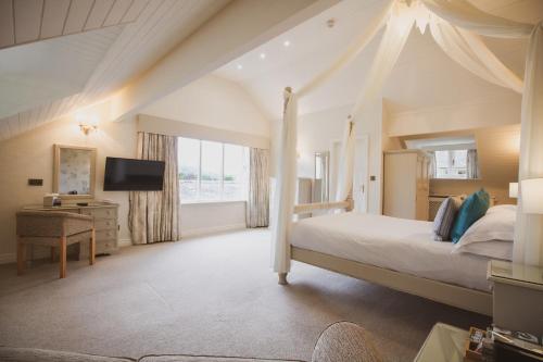 a bedroom with a canopy bed and a television at Cragwood Country House Hotel in Windermere