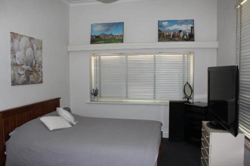a bedroom with a bed and a television and a window at The Cosy House - Central Albury in Albury