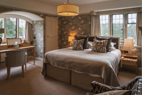 a bedroom with a large bed and a desk and chairs at Cragwood Country House Hotel in Windermere