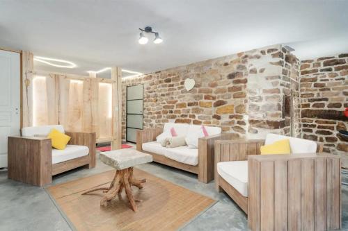 a living room with wooden furniture and a brick wall at Piscine Spa et Sauna Privé in Uzemain