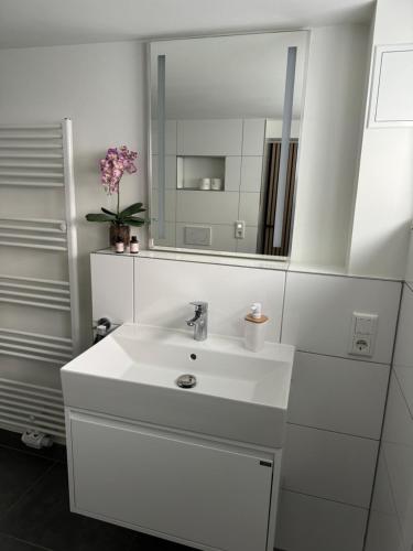 a white bathroom with a sink and a mirror at Modernes Apartment, ruhige Lage, stadtnah in Kelkheim