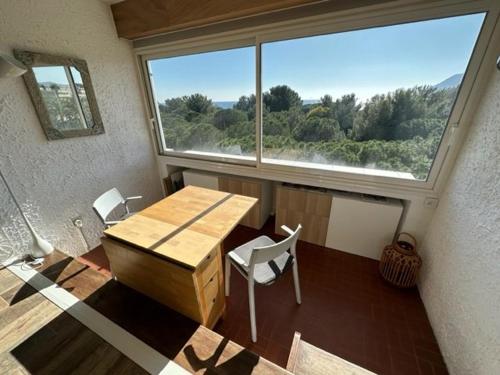 une pièce avec une table et des chaises et une grande fenêtre dans l'établissement Vue mer, plage des Sablettes à pied et climatisation, à La Seyne-sur-Mer
