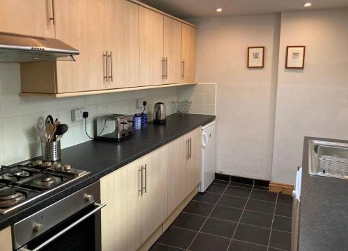 Una cocina con gabinetes blancos y una encimera negra. en Tenby Cottage with Parking, en Tenby