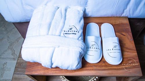 two white mittens and a pair of slippers on a table at The Telescope Boutique Lodge in Victoria Falls