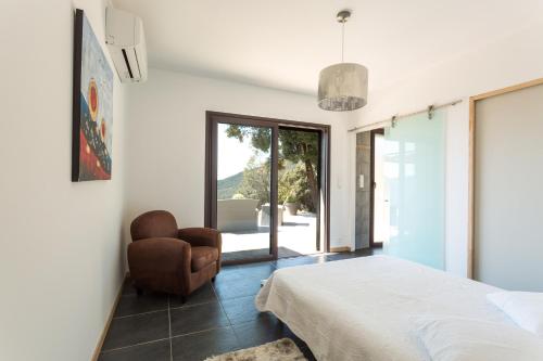 - une chambre avec un lit, une chaise et une fenêtre dans l'établissement Villa Kalliste, à Olmeto
