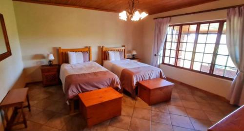 a bedroom with two beds and a large window at The Ivy Cottage at Random Rocks Farm in Tonteldoos