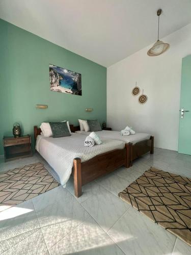 a bedroom with a large bed with green walls at No Name Apartments in Laganas