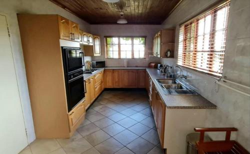 a kitchen with wooden cabinets and a black appliances at The Ivy Cottage at Random Rocks Farm in Tonteldoos