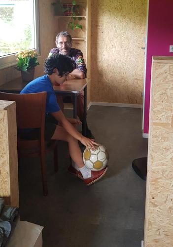 Um homem e um rapaz sentados à mesa com uma bola de futebol. em Huisje de Bosrand em Bant