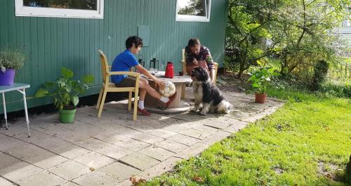 duas pessoas e um cão sentado à mesa em Huisje de Bosrand em Bant
