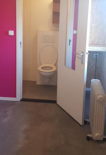 uma casa de banho com um WC e uma porta rosa em Huisje de Bosrand em Bant