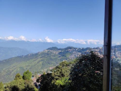 een uitzicht op een heuvel met bomen en de oceaan bij Royoporus Taktsang Darjeeling in Darjeeling