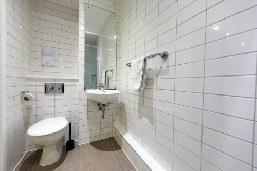 a white tiled bathroom with a toilet and a sink at University of Bath City Accommodation in Bath