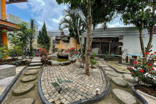 Salsabila Villa Syariah RedPartner في Kedemangan-wetan: حديقة فيها اشجار وورود امام مبنى