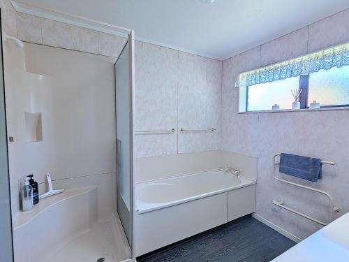 a white bathroom with a tub and a sink at Available Now! Family home near Redwood Forest in Rotorua