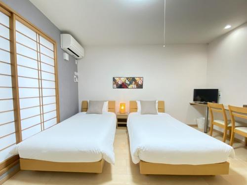 two beds in a room with a tv at Kyoto Tabisou Kasumi in Kyoto