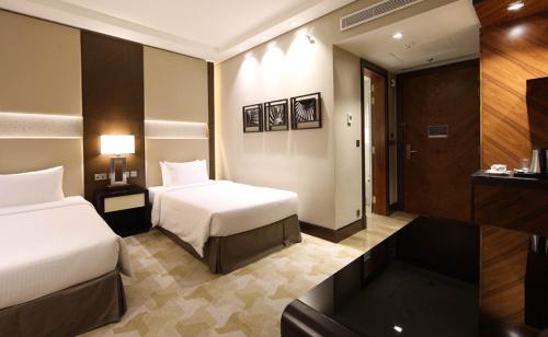 a hotel room with two beds and a television at Aerotel Jeddah in Jeddah