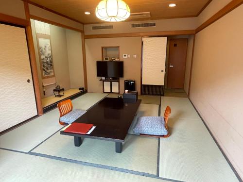 a living room with a table and chairs and a tv at Ryokan Ichinomatsu in Hakodate