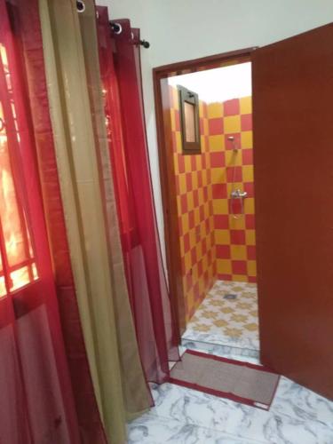 a bathroom with a red door and a yellow tile shower at Sawadogo meublée in Ouagadougou