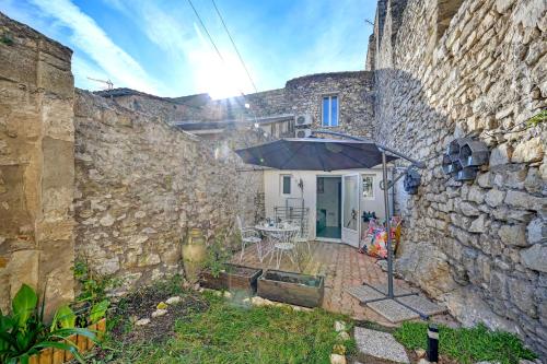 a stone house with an umbrella in a courtyard at La Cigale - Vieux Village - Charmante Maisonnette climatisée avec Jardin in Villeneuve-lès-Avignon