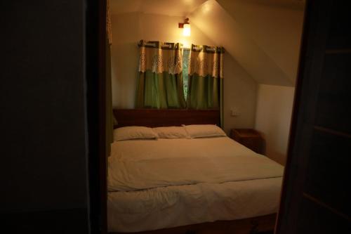 a bedroom with a bed and a window with curtains at SpiceBuds TreeHouse - Idukki in Ramakkalmedu