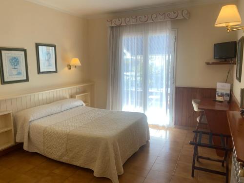 1 dormitorio con cama, escritorio y ventana en Casa feliu, en Santa Susanna