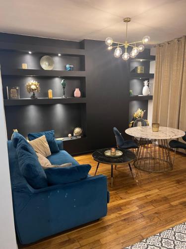 ein Wohnzimmer mit einem blauen Sofa und einem Tisch in der Unterkunft Rosny01 Luxueux Gare Disney Paris in Rosny-sous-Bois