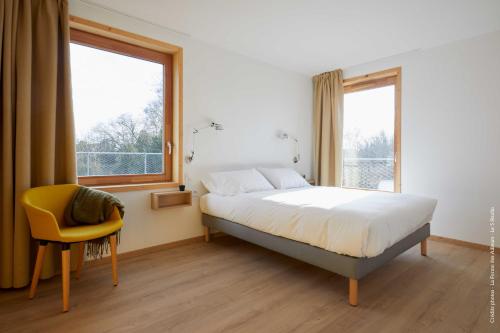 een slaapkamer met een bed en een gele stoel bij La Ferme Des Ailleurs in Arleux-du-Nord