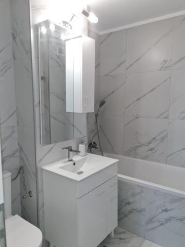 a white bathroom with a sink and a mirror at Seaview Residence in Constanţa