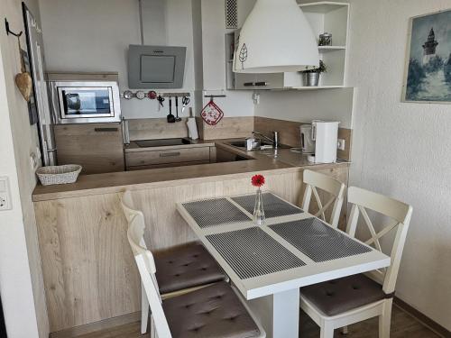 eine kleine Küche mit einem Tisch und Stühlen in einem winzigen Haus in der Unterkunft Strandhotel Wohnung 30 in Dahme