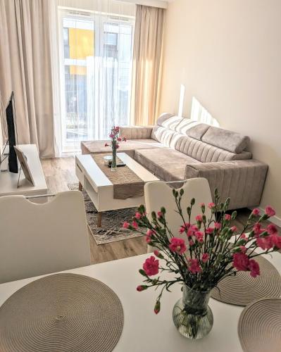 sala de estar con sofá y mesa con flores en Apartament Leomar, bezkontaktowe zameldowanie, darmowy parking, en Poznan