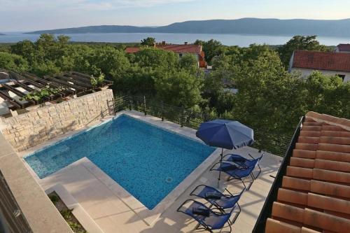 una piscina con due sedie e un ombrellone di Welcome to Island Krk! a Linardići