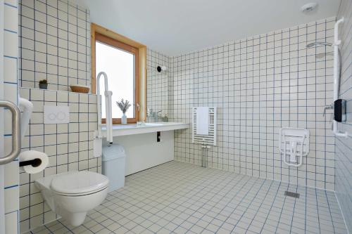 a tiled bathroom with a toilet and a sink at La Ferme Des Ailleurs in Arleux-du-Nord