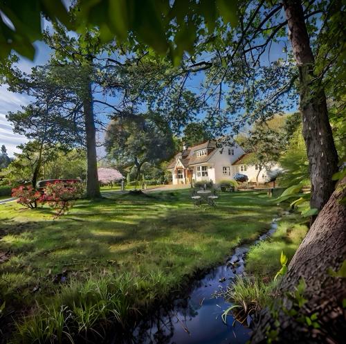 a house with a stream in the yard at Daweswood - Luxury cottage, lake access & hot tub in Canterbury