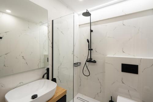 a white bathroom with a shower and a sink at The Edge - Luxury Residences in Athens