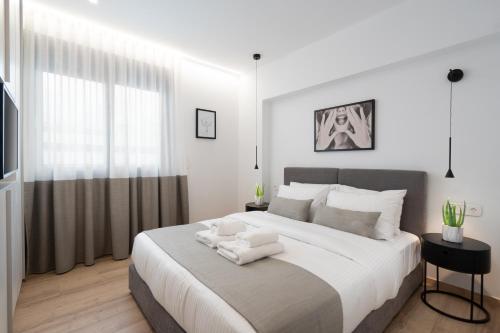 a white bedroom with a large bed with two towels on it at The Edge - Luxury Residences in Athens