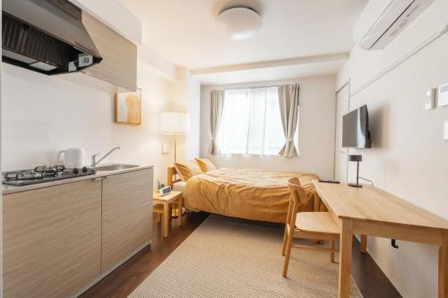 a small bedroom with a bed and a table and a kitchen at Float Inn Asakusa in Tokyo