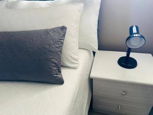 ein Bett mit einem Kissen und einer Lampe auf einem Nachttisch in der Unterkunft The Sails One Bedroom Apartment in Durban
