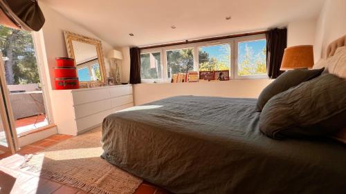 um quarto com uma cama, um espelho e janelas em LA CIVADE em La Ciotat