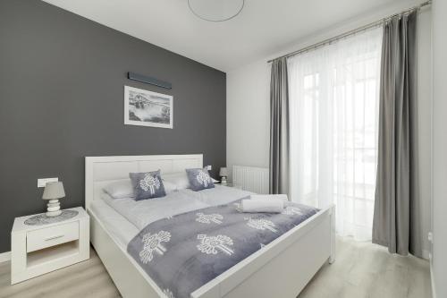 Un dormitorio con una cama blanca y una ventana. en Szymony Apartments Zakopane with SPA & Parking by Noclegi Renters, en Zakopane