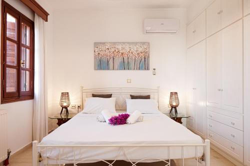 a bedroom with a white bed with flowers on it at Villa Sea View Gem Steps to Zia Square Hot Tub in Lagoúdi Zía
