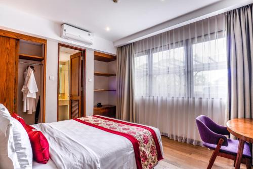 a bedroom with a bed and a table and a window at Royal Tulip Springhill Resort Jimbaran in Jimbaran